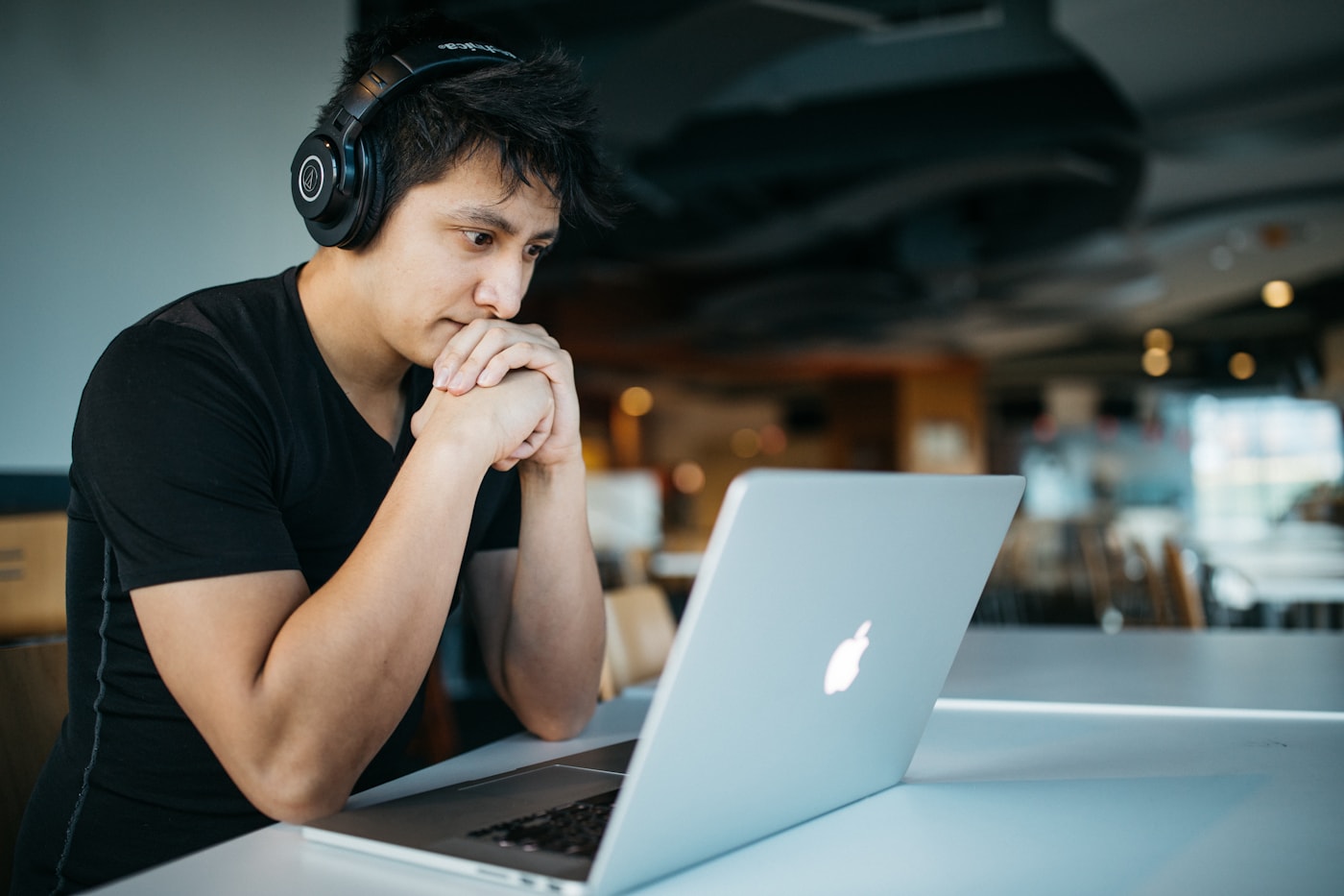Jovem com fones de ouvido em frente ao notebook estudando